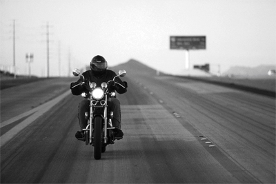 A Lone Biker Riding a Motorcycle In The Wind